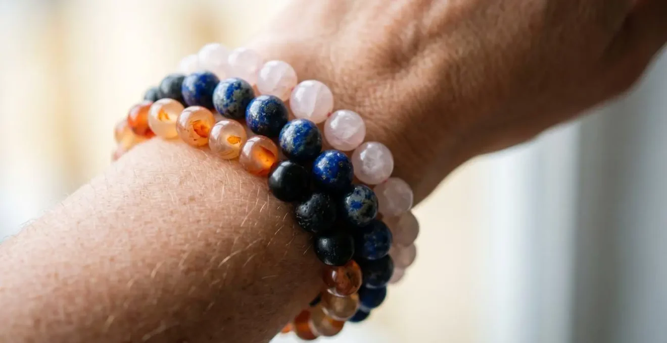 Gros plan sur un poignet portant plusieurs bracelets en pierres naturelles colorées, capturant la texture et les nuances énergétiques sans texte visible