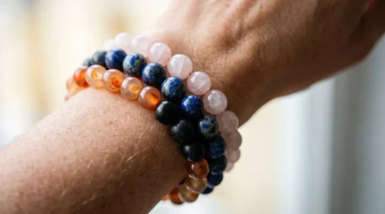 Gros plan sur un poignet portant plusieurs bracelets en pierres naturelles colorées, capturant la texture et les nuances énergétiques sans texte visible
