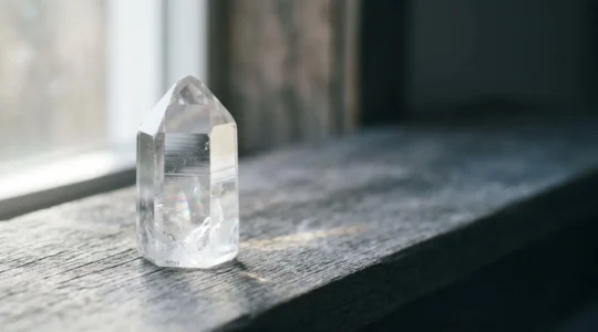 Cristal de roche transparent posé dans une ambiance lumineuse naturelle évoquant la clarté et la manifestation d'intentions