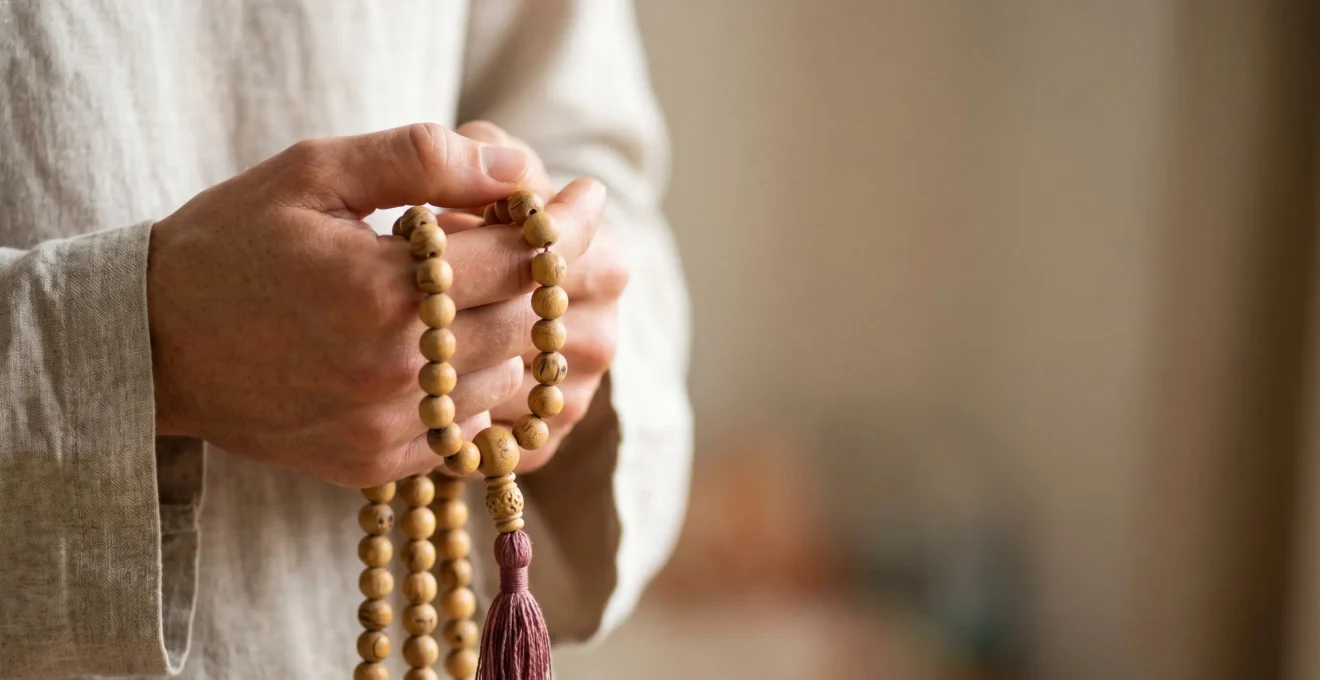 Mala de méditation en bois de santal tenu délicatement entre les doigts pour la récitation de mantras
