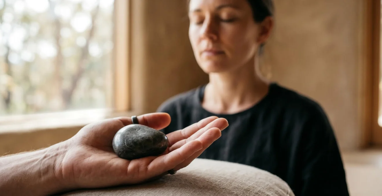 Personne en méditation tenant délicatement une pierre lisse dans la main gauche, dans une atmosphère apaisante et contemplative
