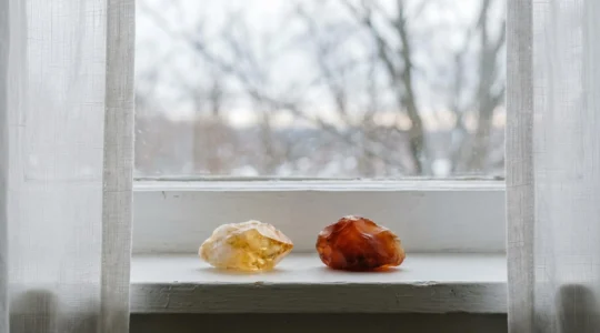 Pierre de citrine jaune et cornaline orange disposées sur un rebord de fenêtre baigné de lumière douce hivernale