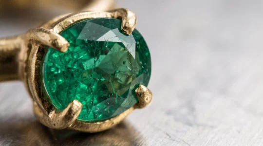 Gros plan sur une pierre précieuse sertie dans une monture en métal précieux, révélant les détails du sertissage artisanal
